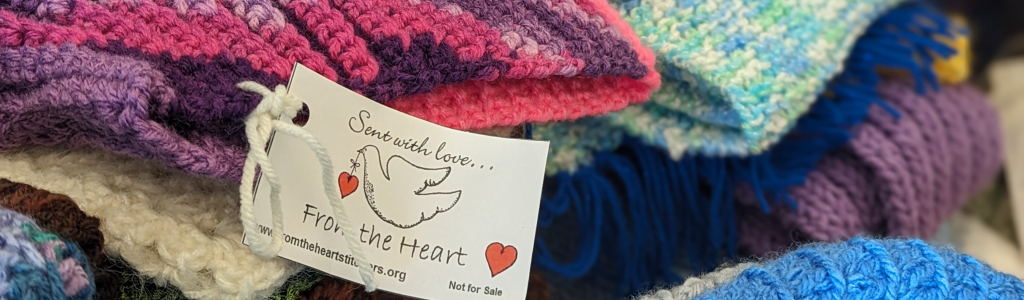 A white tag with the image of a dove attached to a pile of knitted items.